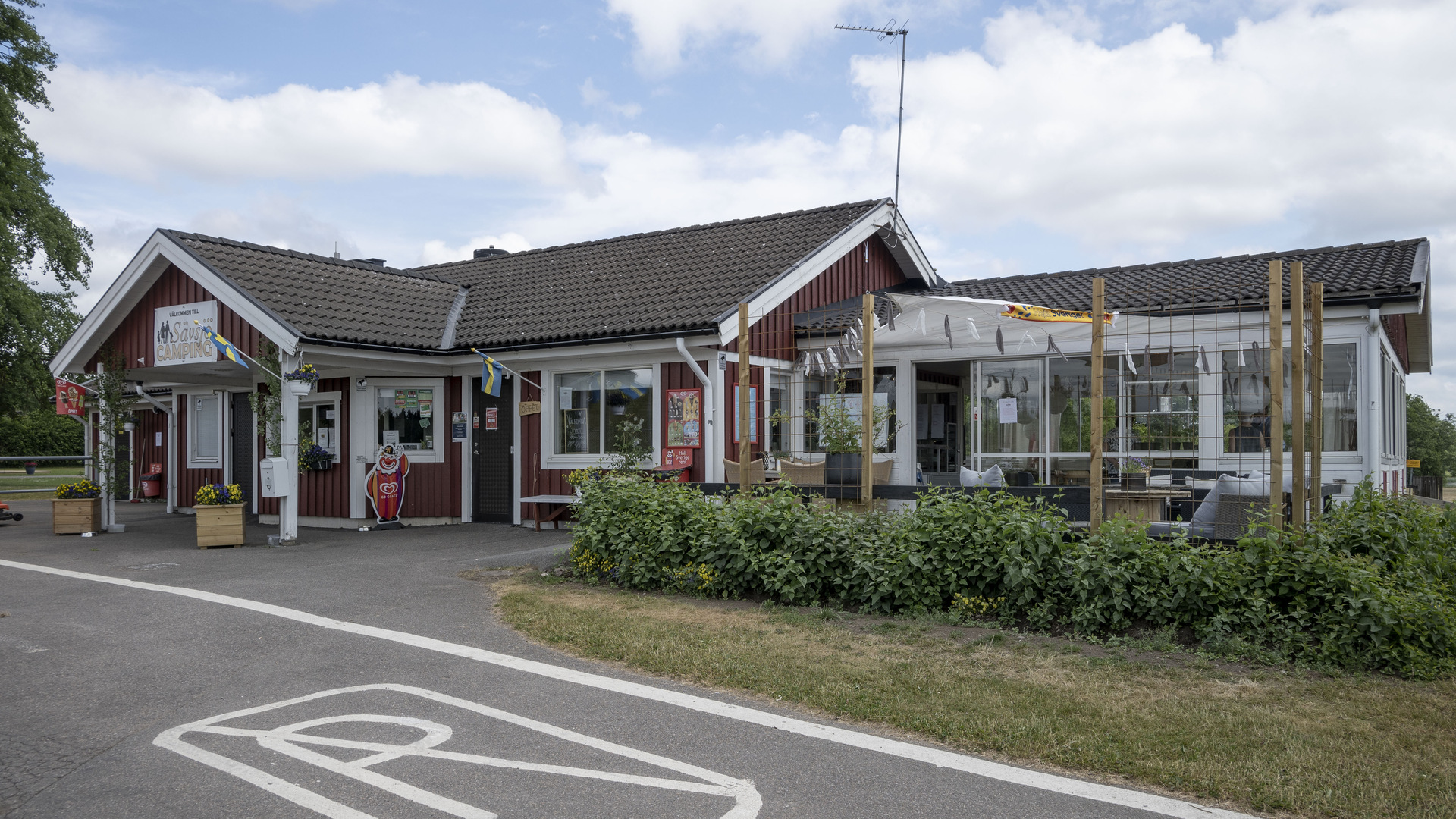 Röd träbyggnad med cafédel och service.