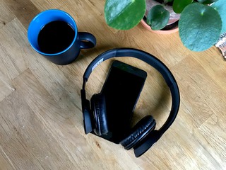 Kaffekopp, telefon och lurar på ett bord