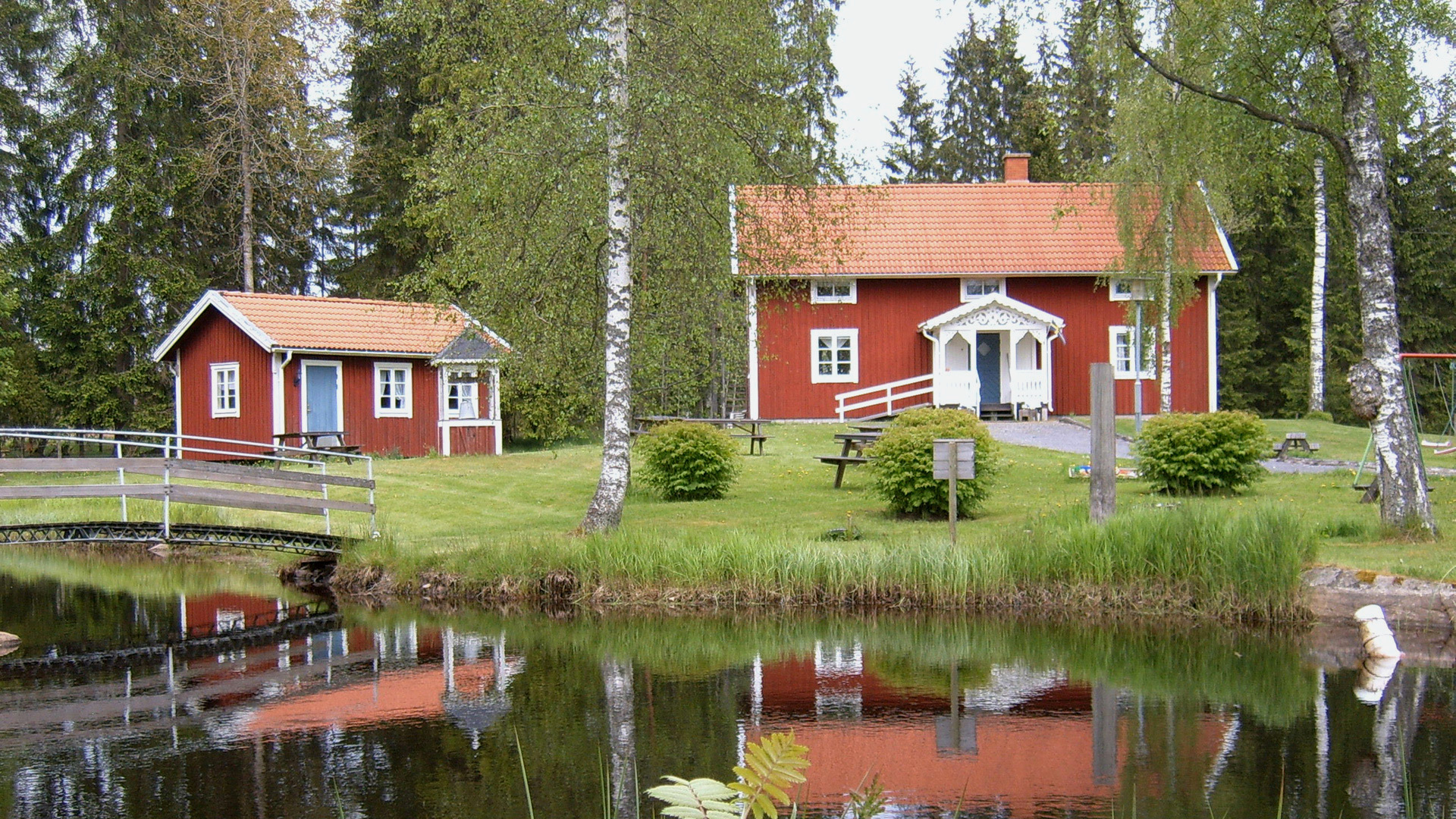 Två röda stugor vid en damm.