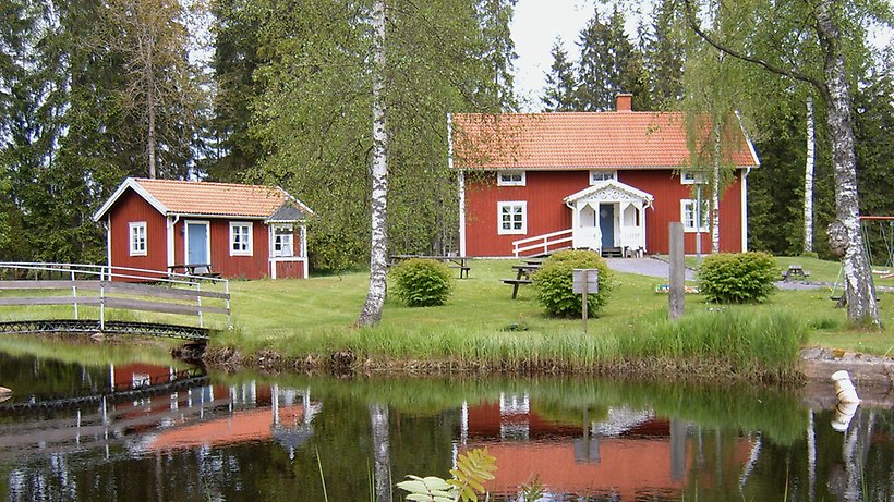 Två röda stugor vid en vattensamling